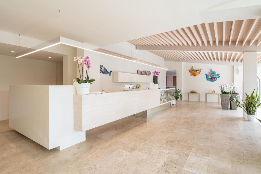 un hall d'entrée avec un comptoir avec des fleurs dessus dans l'établissement Ricci Hotel - Marina di Grosseto, à Marina di Grosseto