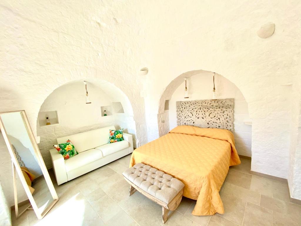 - une chambre blanche avec un lit et un canapé dans l'établissement Trulli Paradise Alberobello, à Alberobello