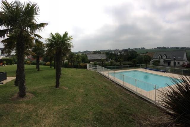 une piscine dans une cour avec deux palmiers dans l'établissement Gite - Le Toucan - Maison avec Terrasse dans parc avec piscine proche plages et Golf, à Pléneuf-Val-André