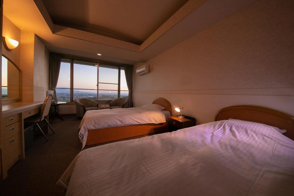 une chambre d'hôtel avec deux lits, un bureau et une fenêtre dans l'établissement Omuta Heights, à Ōmuta