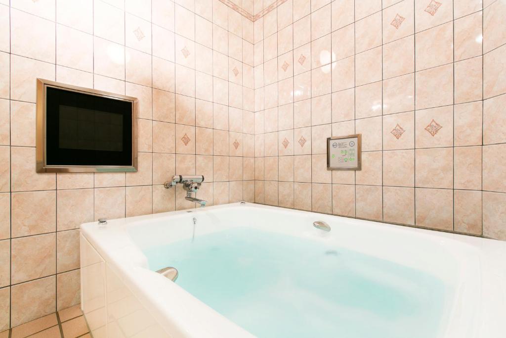 La salle de bains carrelée est pourvue d'une baignoire et d'une télévision. dans l'établissement Hotel Luna (Adult Only), à Sennan
