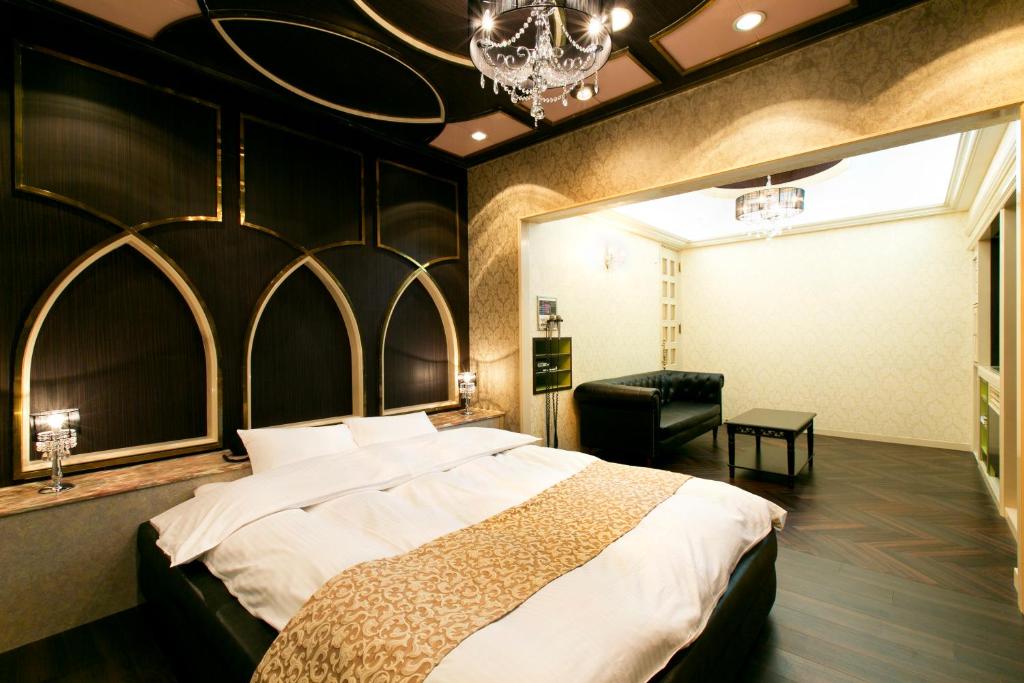une chambre avec un grand lit et un lustre dans l'établissement Hotel Luna (Adult Only), à Sennan