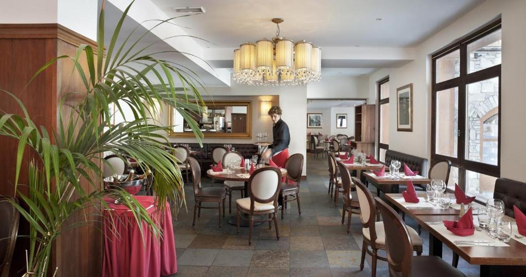 un homme debout dans un restaurant avec des tables et des chaises dans l'établissement Arc 1950 3 pièces 6 personnes Luxe Manoir Savoie, à Arc 1950