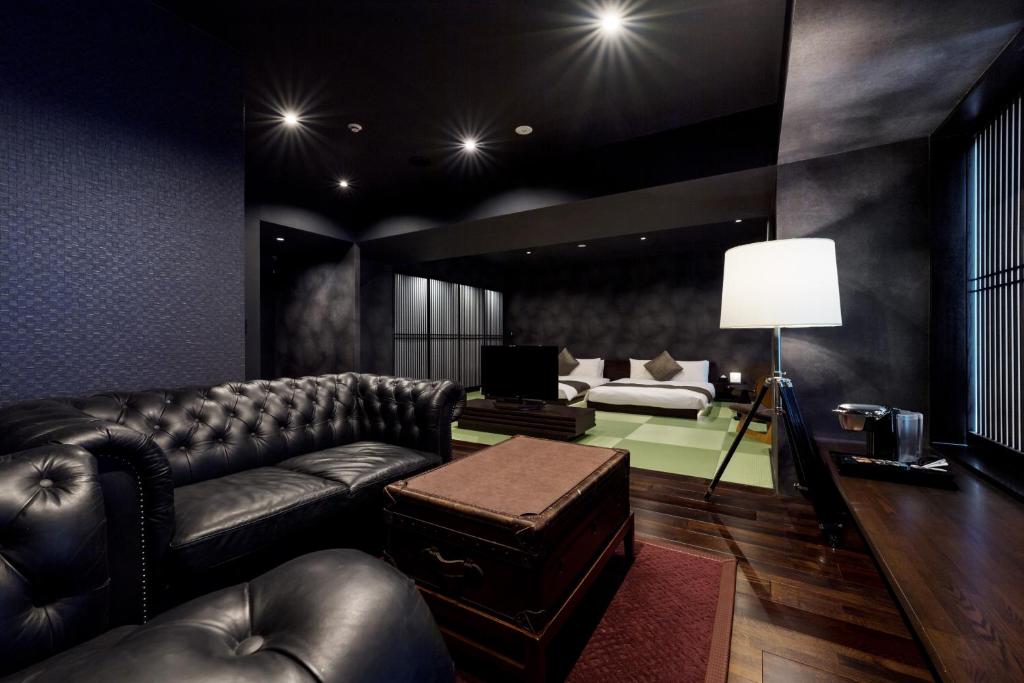 - un salon avec un canapé en cuir et un lit dans l'établissement PROSTYLE Ryokan Yokohama Bashamichi, à Yokohama
