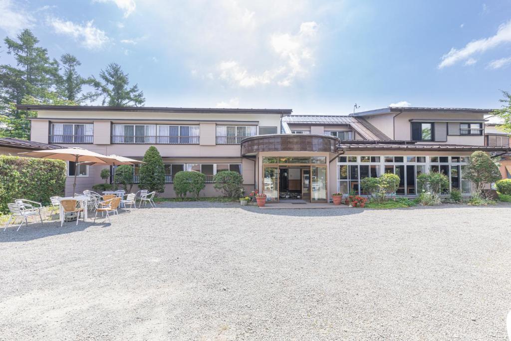 une grande maison avec des tables et des chaises en face de celle-ci dans l'établissement Hanamizuki, à Yamanakako