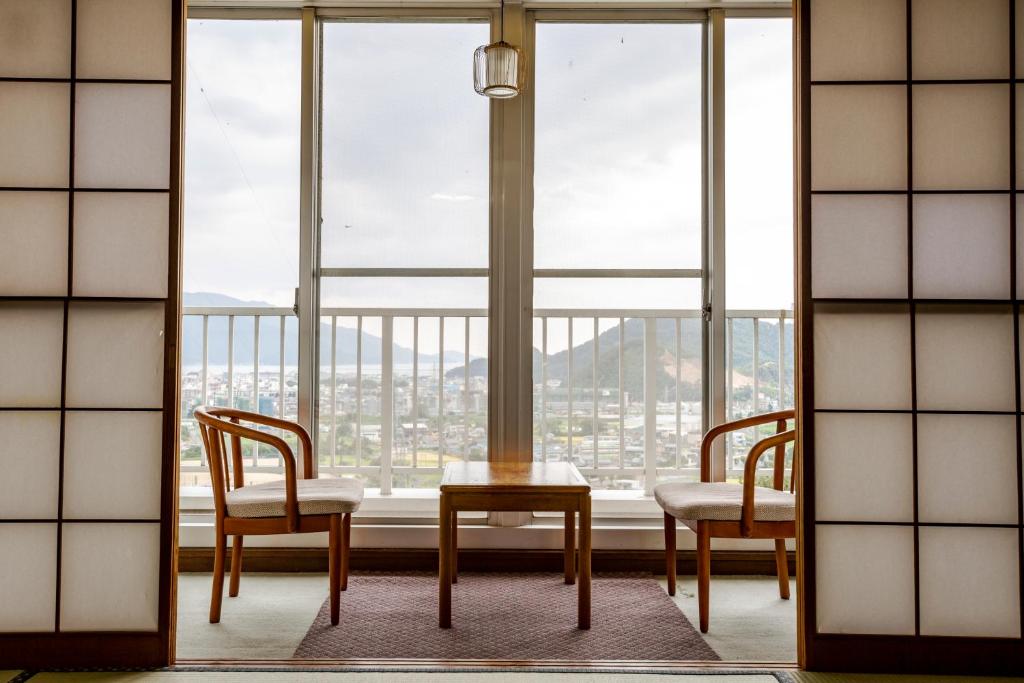 une chambre avec deux chaises et une table devant une fenêtre dans l'établissement Tsuruga Tunnel Onsen Kitaguni Grand Hotel, à Tsuruga