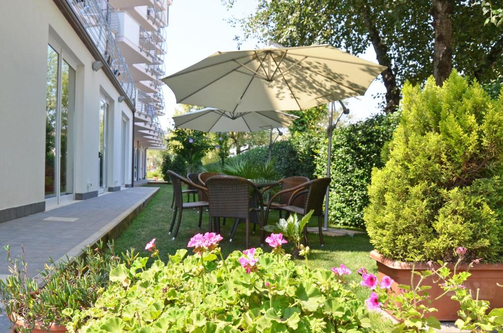 une terrasse avec un parasol, des chaises et des fleurs dans l'établissement Hotel La Ninfea, à Montesilvano