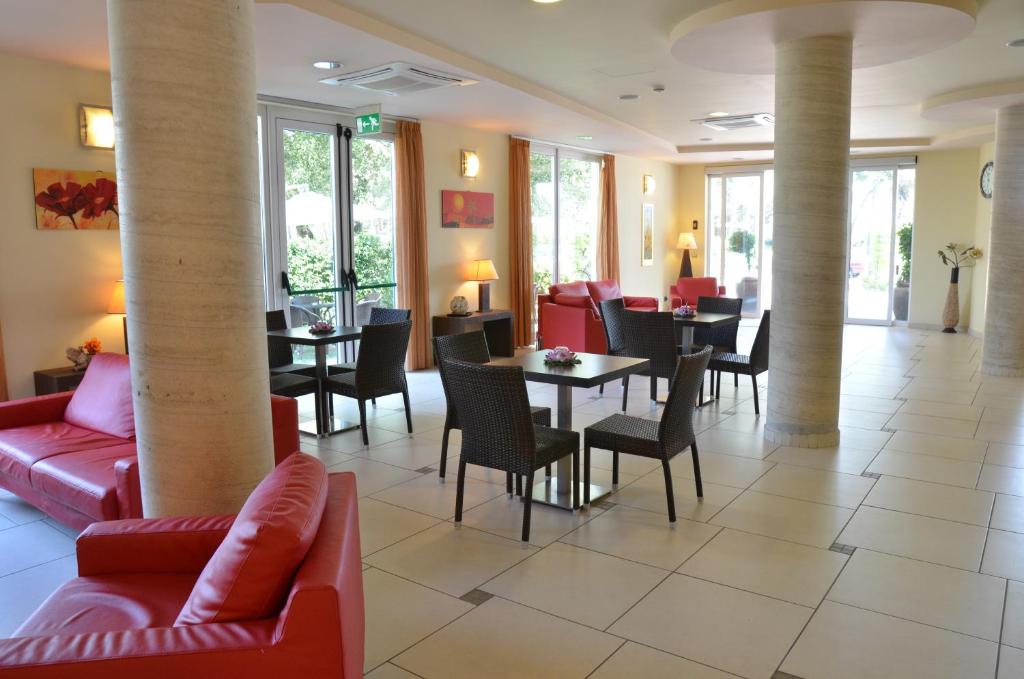 un restaurant avec des canapés rouges, des tables et des chaises dans l'établissement Hotel La Ninfea, à Montesilvano