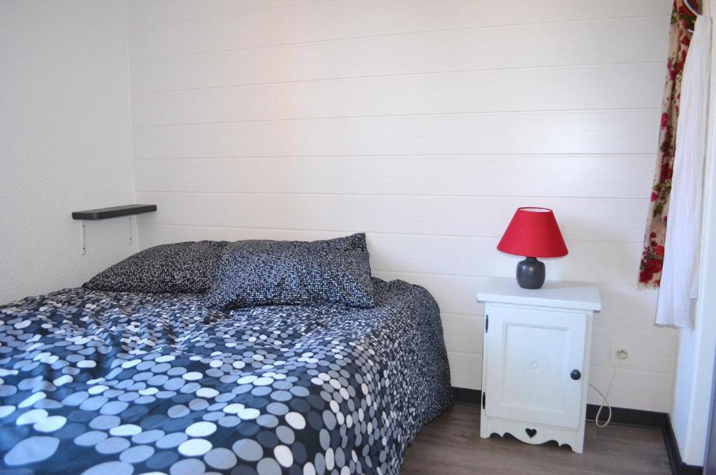 - une chambre avec un lit et une lampe rouge sur une table de chevet dans l'établissement Belle Plagne 1 Appart 6 pers du Dimanche au Dimanche Ski au pieds, à La Plagne