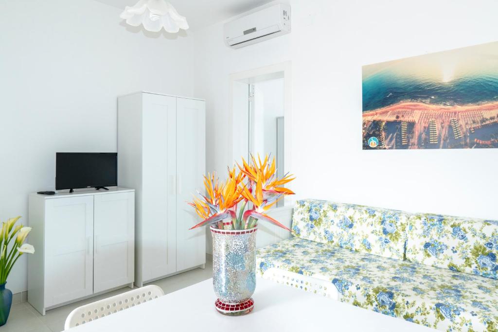 un salon avec un canapé et une table avec des fleurs dans l'établissement Centro Vacanze Lido Smeraldo, à Frigole