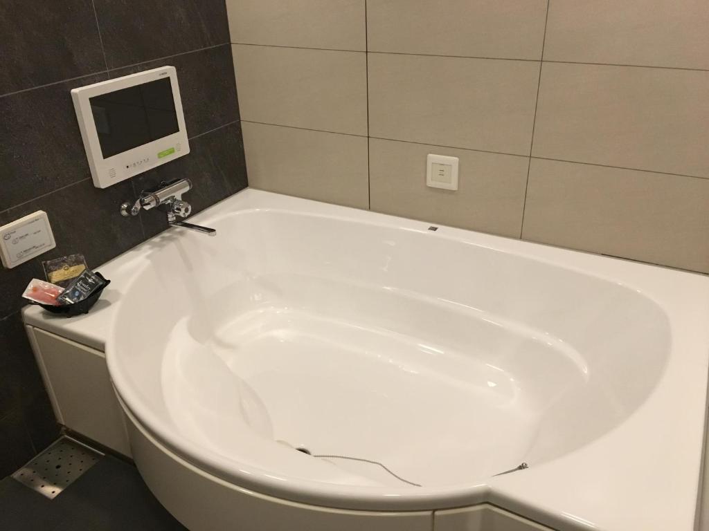 une baignoire dans une salle de bain avec une télévision au mur dans l'établissement Hotel S-CUBE (Adult Only), à Bando 2 autres photos