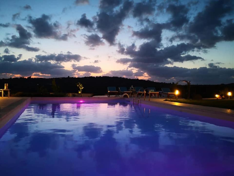 une grande piscine avec un coucher de soleil en arrière-plan dans l'établissement Villa Dama luxury, à Alghero