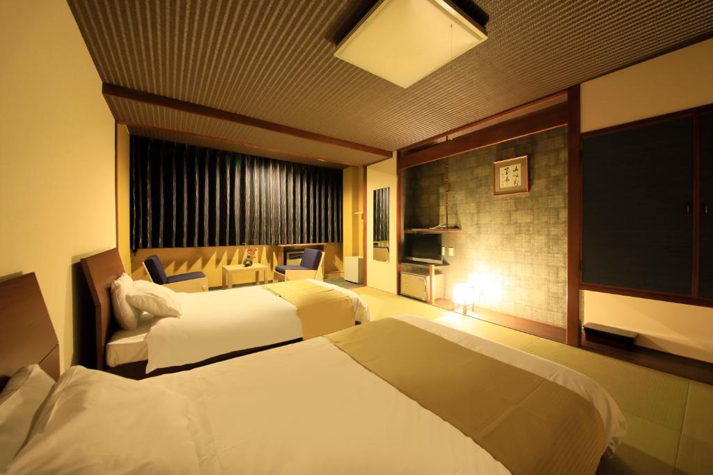 une chambre d'hôtel avec deux lits et une télévision à écran plat dans l'établissement Yutorelo Toyako, à Lac Tōya
