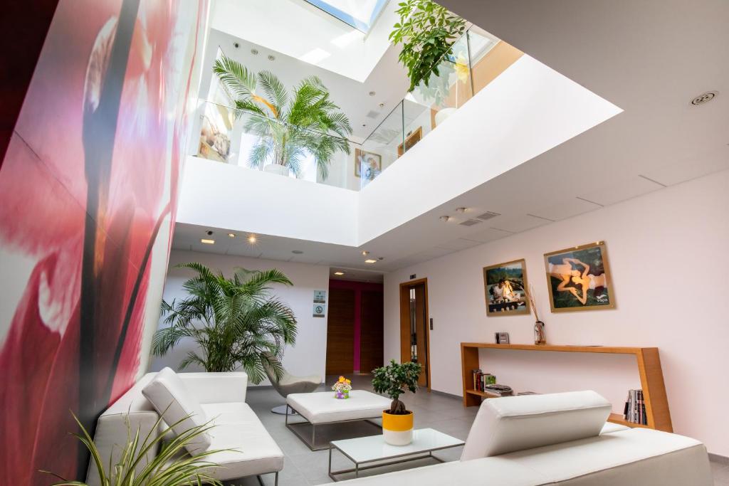 un salon avec des meubles blancs et des plantes dans l'établissement Valentino SPA Resort, à Grottammare