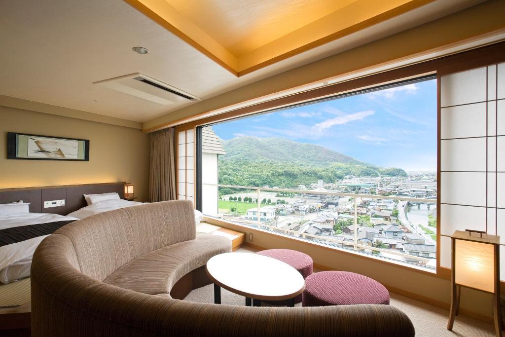 Cette chambre dispose d'une grande fenêtre, d'un lit et d'un canapé. dans l'établissement Yumoto Konpira Onsen Hananoyu Kobaitei, à Kotohira