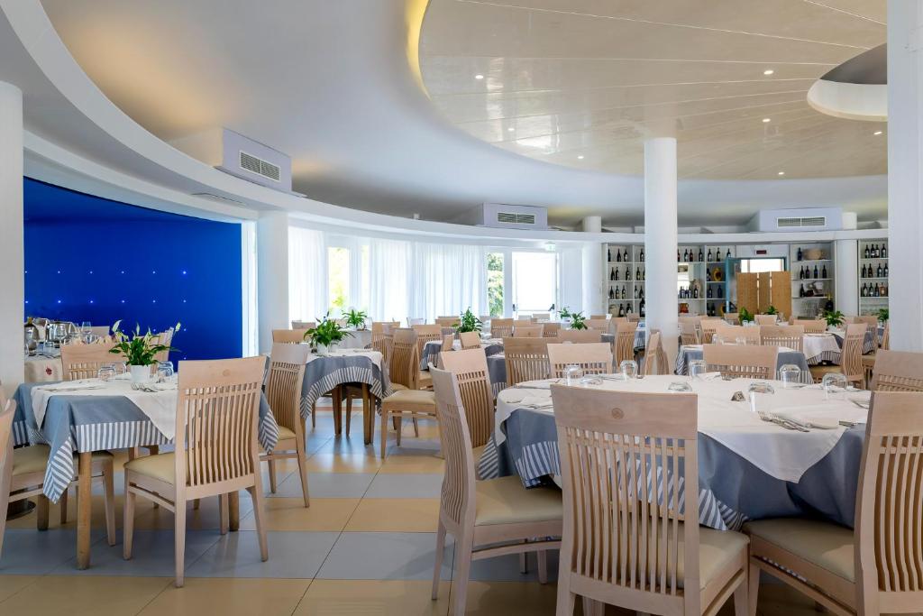 un restaurant avec des tables et des chaises blanches et un mur bleu dans l'établissement Hotel Villaggio Stromboli, à Santa Domenica