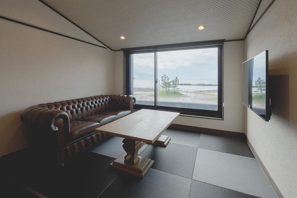 une chambre avec un canapé, une table et une fenêtre dans l'établissement Arujisu, à Izu