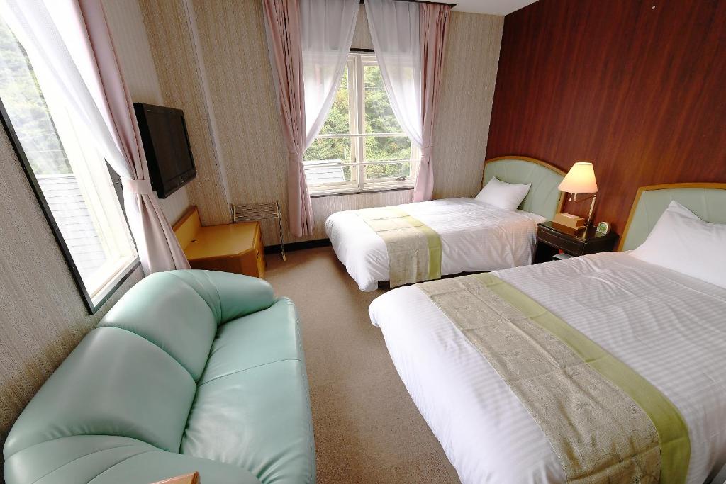 une chambre d'hôtel avec deux lits et un canapé dans l'établissement Hotel Ra Kuun, à Hakone