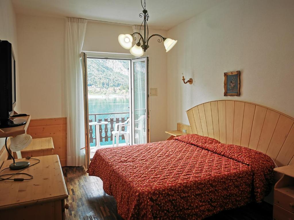 - une chambre avec un lit doté d'un couvre-lit rouge et d'une fenêtre dans l'établissement Lago Park Hotel, à Molveno