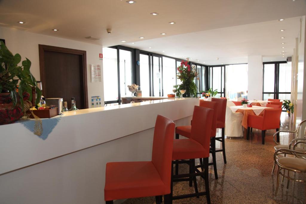 un restaurant avec un bar doté de chaises et de tables rouges dans l'établissement Hotel San Carlo, à Lignano Sabbiadoro