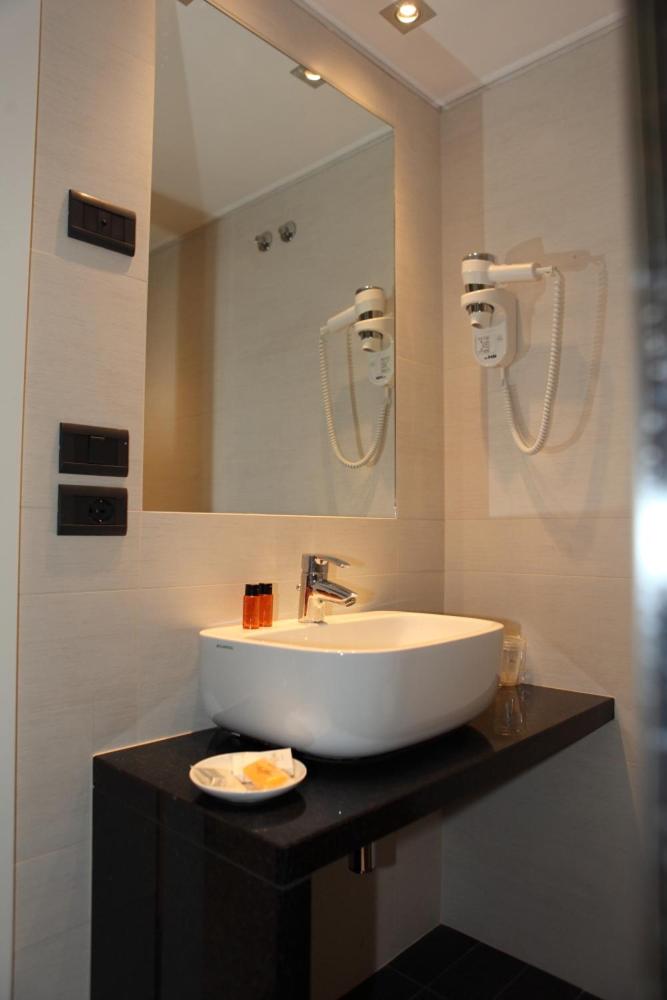 une salle de bain avec un lavabo et un miroir dans l'établissement Hotel San Carlo, à Lignano Sabbiadoro