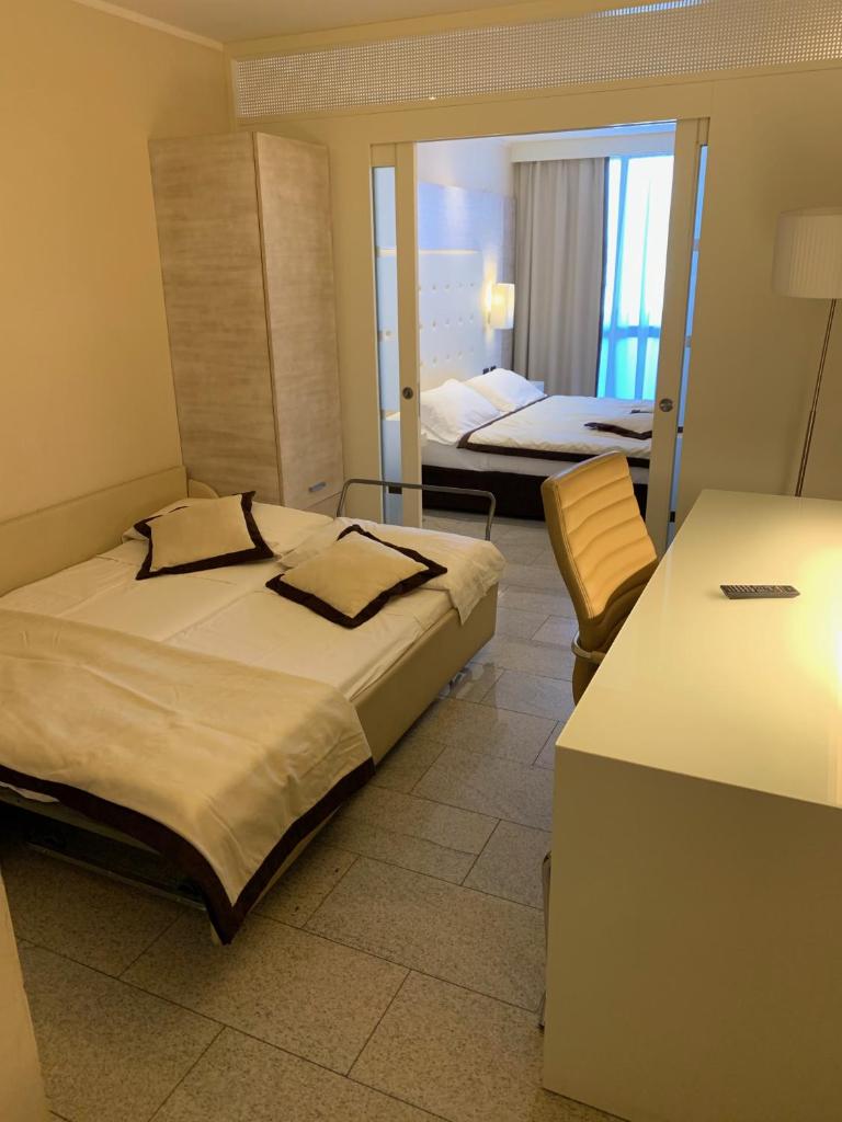 une chambre d'hôtel avec deux lits et un miroir dans l'établissement Hotel San Carlo, à Lignano Sabbiadoro 34 autres photos