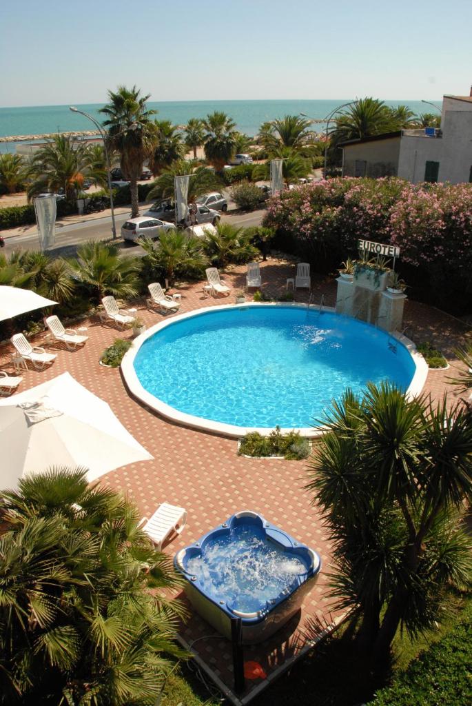 une grande piscine avec des chaises et l'océan dans l'établissement Eurotel, à Grottammare