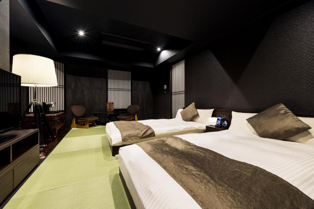 une chambre d'hôtel avec deux lits et une télévision dans l'établissement PROSTYLE Ryokan Yokohama Bashamichi, à Yokohama