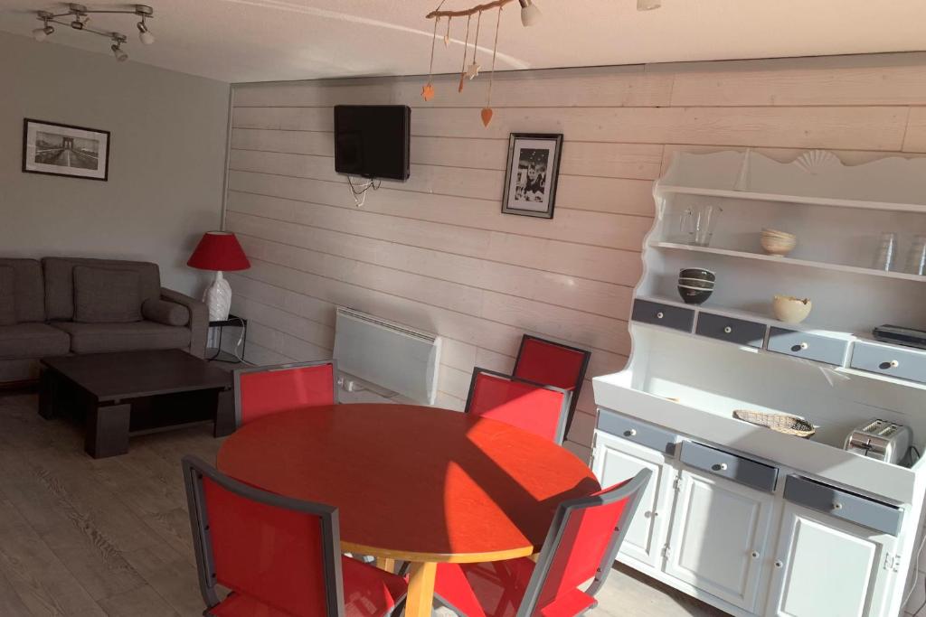 une salle à manger avec une table et des chaises rouges dans l'établissement SERRE CHEVALIER 1200, à Briançon
