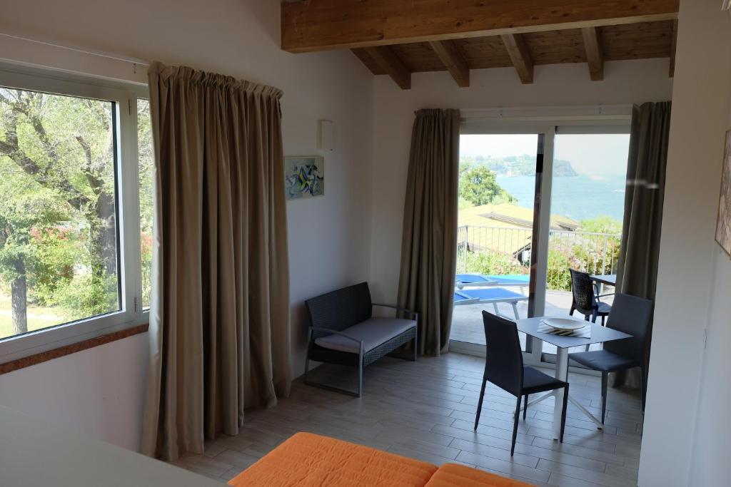 Cette chambre dispose d'une table, de chaises et d'un balcon. dans l'établissement Campeggio Villaggio San Giorgio Vacanze, à Manerba del Garda