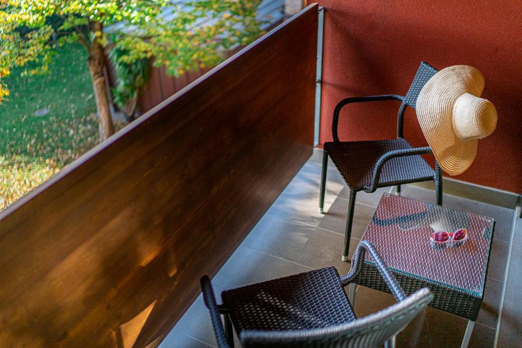 2 chaises et un chapeau installés sur une terrasse couverte dans l'établissement Hotel La Pergola, à Lignano Sabbiadoro