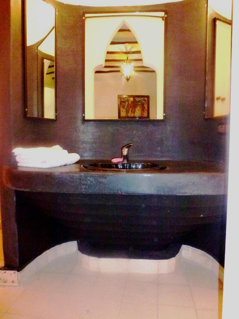 une salle de bain avec un lavabo et deux miroirs dans l'établissement Ryad Laârouss Family, à Marrakech