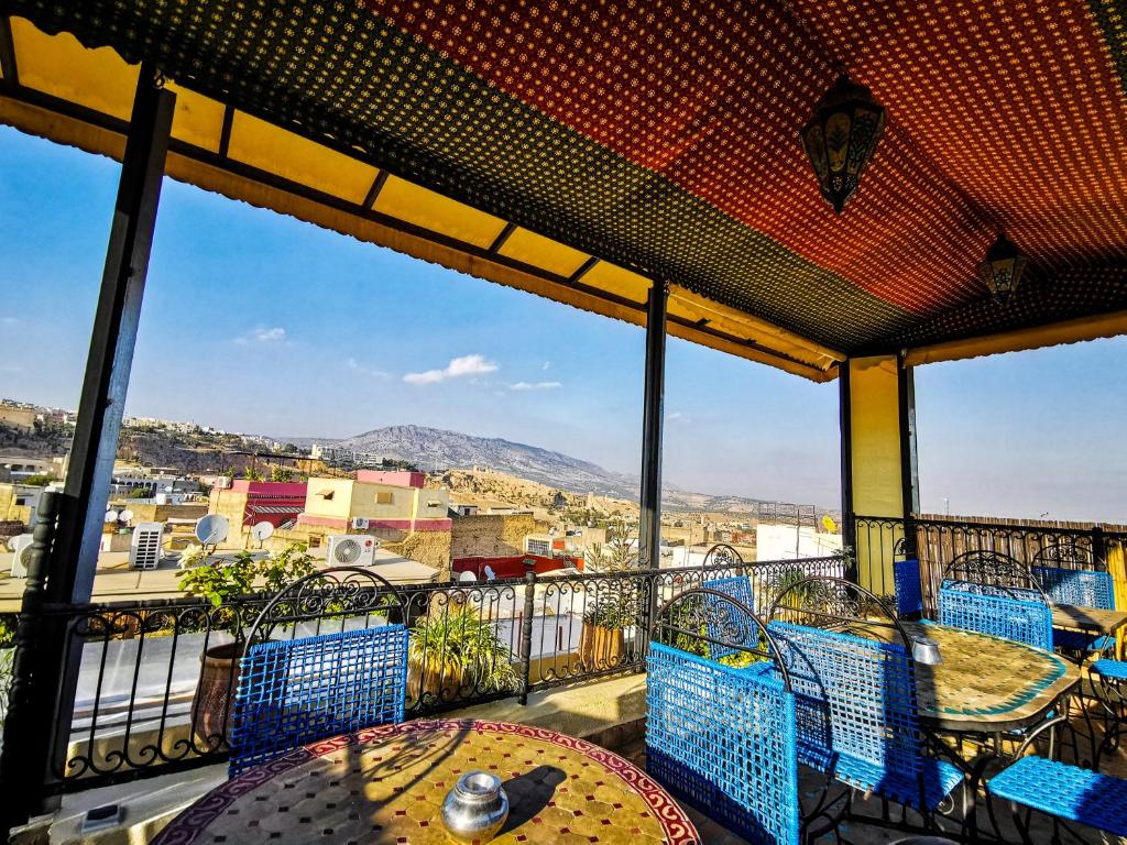 un balcon avec tables et chaises et vue sur la ville dans l'établissement Riad Farah, à Fès