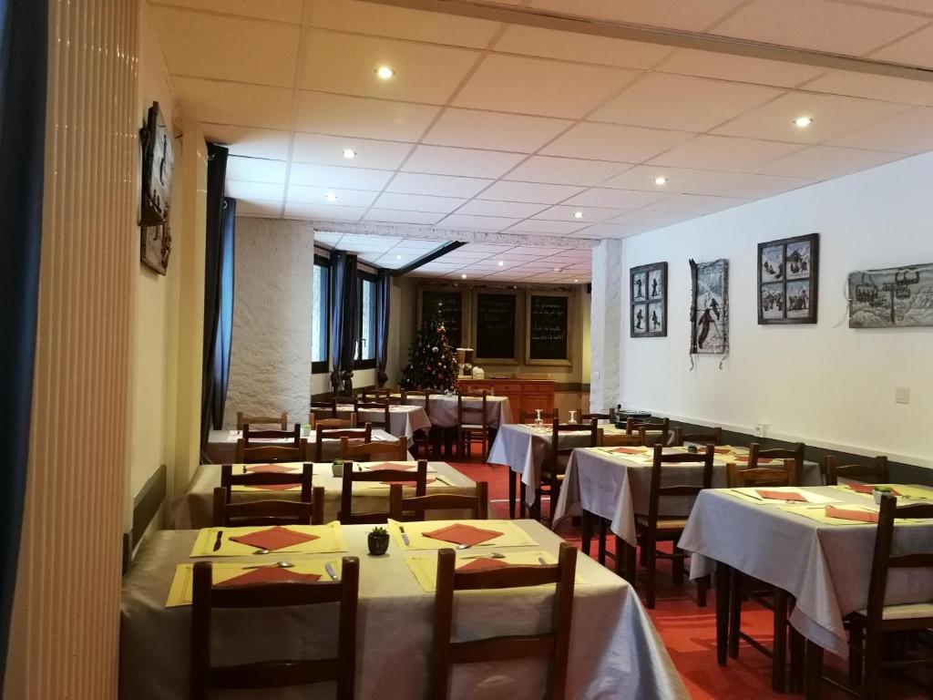 une salle à manger avec des tables et des chaises blanches dans l'établissement Les Carlines, à Vars