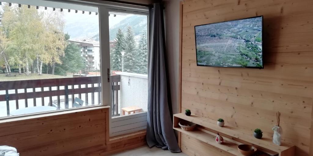 - un salon avec une grande fenêtre et une télévision dans l'établissement Le Galibier, à La Salle Les Alpes
