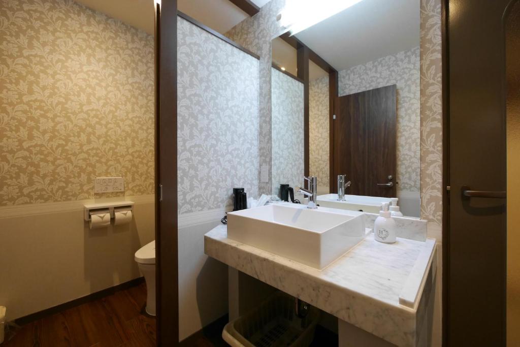 une salle de bain avec un lavabo et des toilettes dans l'établissement Aridagawa Onsen Hotel Sunshine, à Arida
