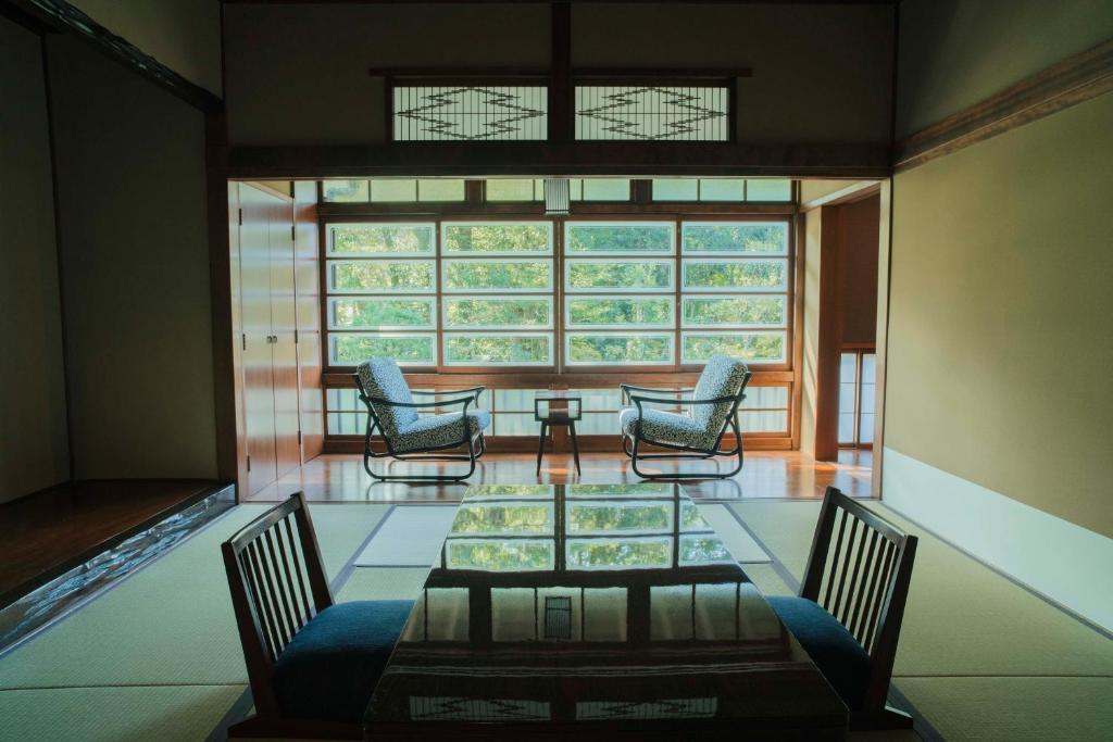 une pièce avec des chaises, une table et une fenêtre dans l'établissement Ochiairo, à Izu