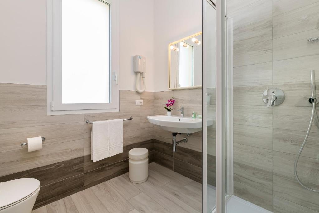 une salle de bain avec un lavabo, des toilettes et une douche dans l'établissement Hotel Zenith, à Cervia