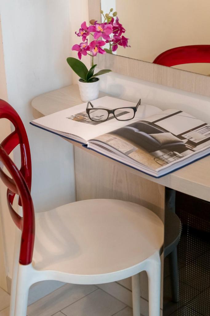un bureau avec une chaise rouge et une table avec un magazine dans l'établissement Hotel Zenith, à Cervia