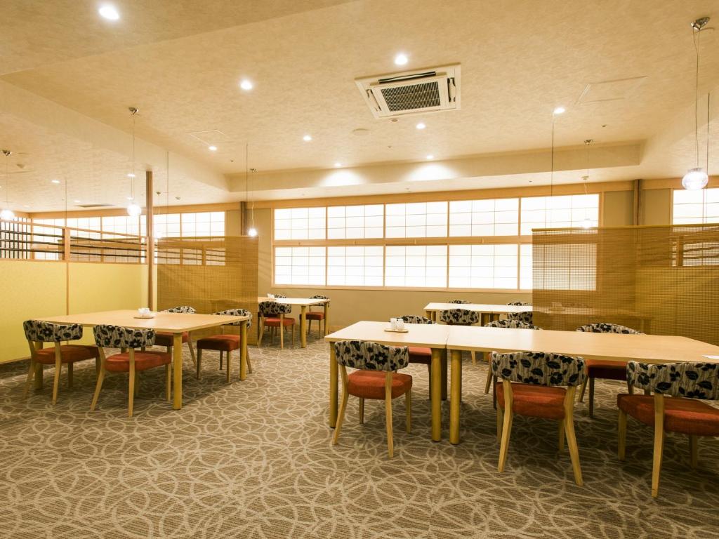 une salle à manger avec tables, chaises et fenêtres dans l'établissement Hanamomiji, à Jozankei 37 autres photos