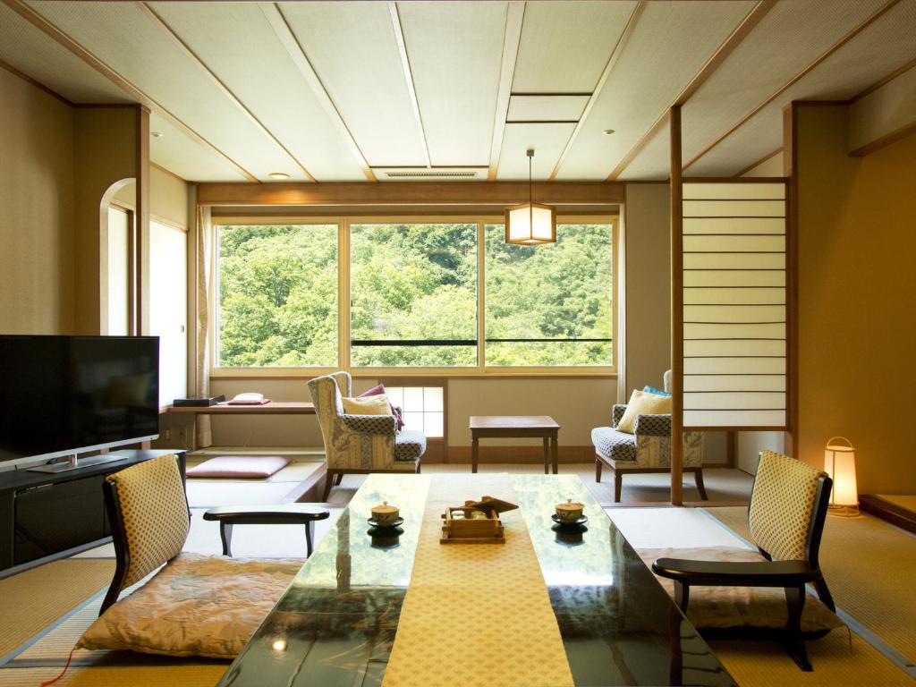 un salon avec une table et une grande fenêtre dans l'établissement Hanamomiji, à Jozankei
