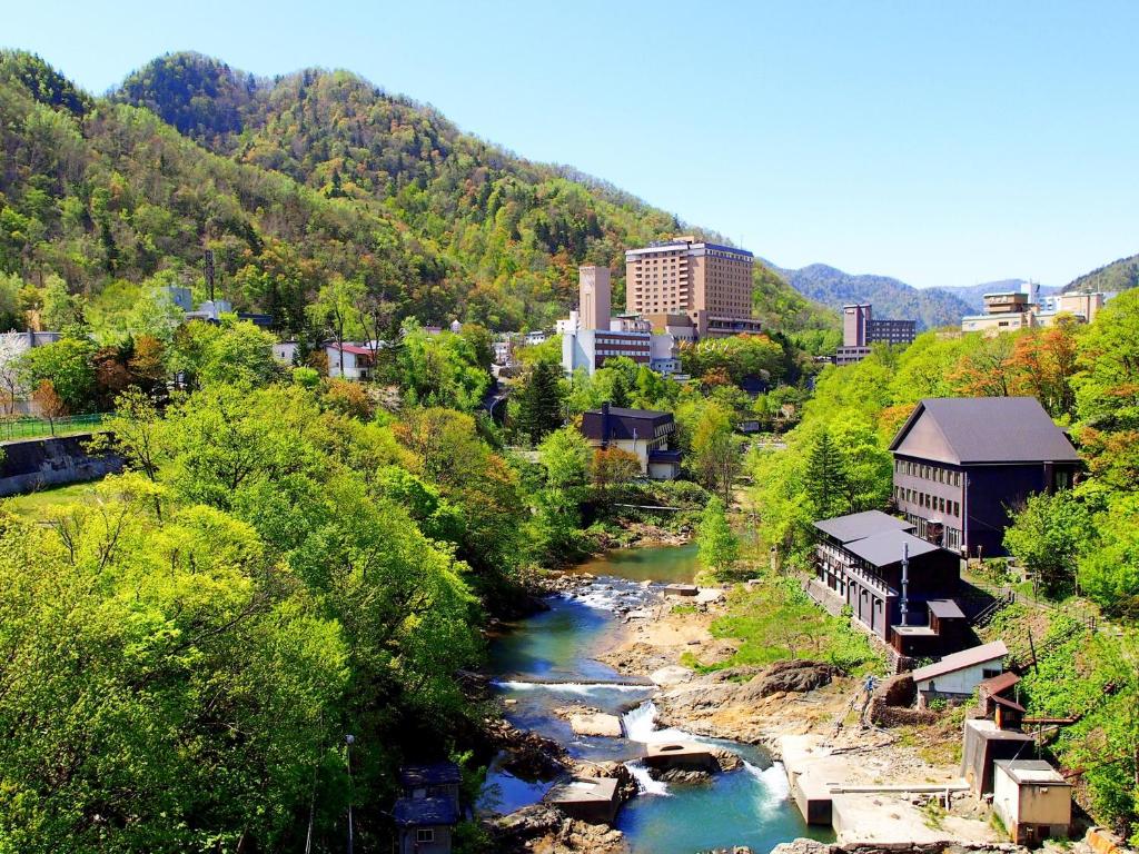une ville avec une rivière, des bâtiments et des arbres dans l'établissement jyozankei Shikanoyu, à Jozankei