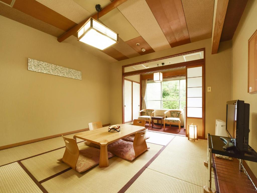 un salon avec une table et une télévision dans l'établissement jyozankei Shikanoyu, à Jozankei