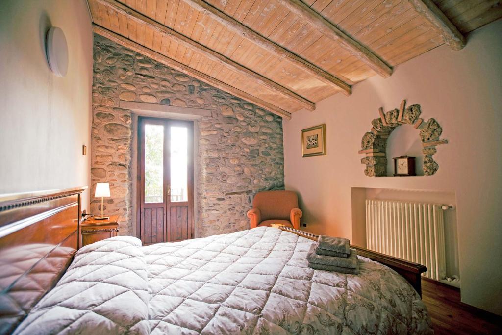 une chambre avec un lit et un mur en pierre dans l'établissement Podere Brughee, à Tremezzo