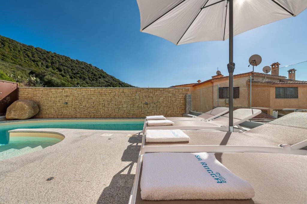 - un ensemble de chaises longues avec un parasol à côté de la piscine dans l'établissement Villa Sa Rocca Manna, à Chia
