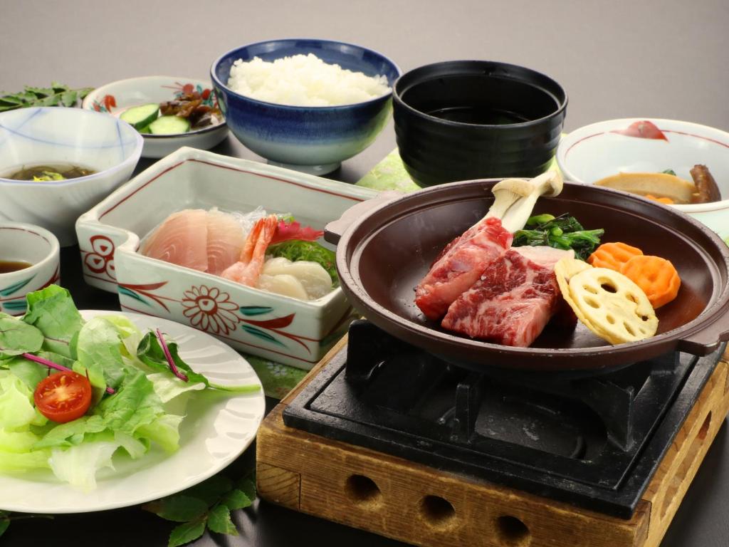 un plat de viande et de légumes sur un grill avec une plaque dans l'établissement Warabiso, à Yuzawa 20 autres photos