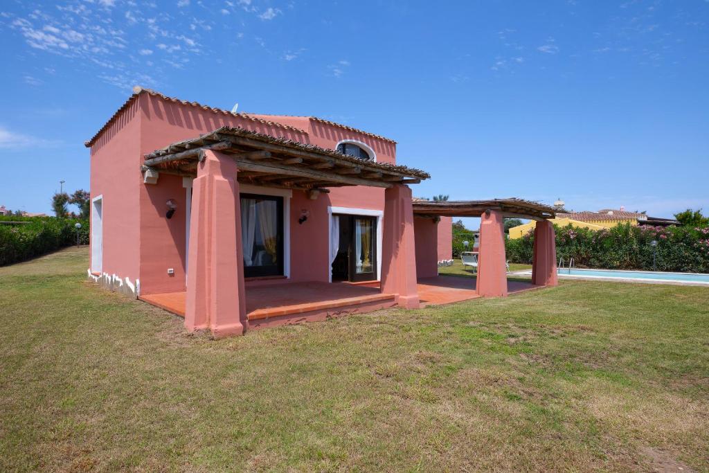 une petite maison rose avec une grande cour dans l'établissement Villa Allegra, à Stintino