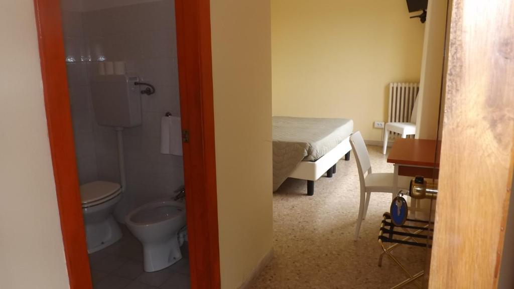 une salle de bain avec un lit et des toilettes dans une chambre dans l'établissement Hotel Cesare, à Giulianova