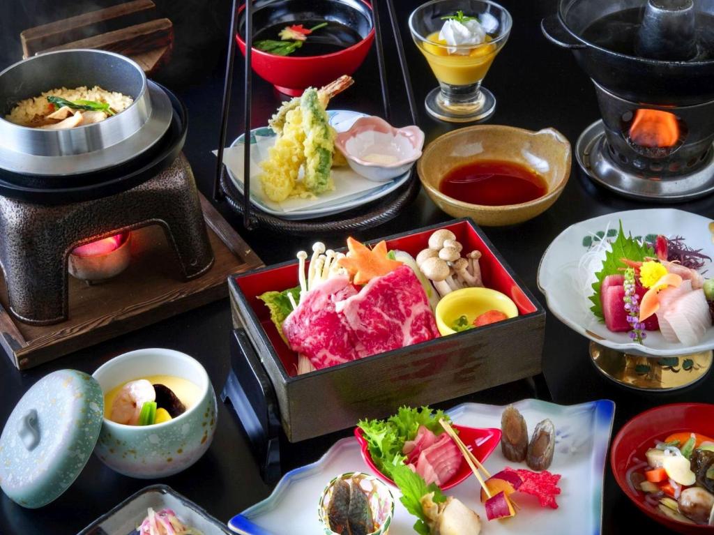 une table recouverte de différents types de nourriture sur les assiettes dans l'établissement Takamiya Hotel Bonari no Mori, à Inawashiro