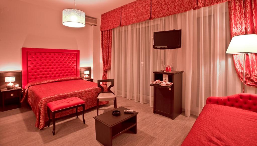 une chambre d'hôtel avec un lit rouge et une chaise dans l'établissement Hotel Nordic, à Bellaria-Igea Marina